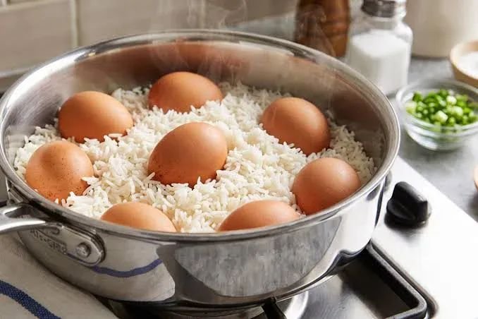 Nigerians cooking rice with boiled eggs in a household kitchen, illustrating food safety and cross-contamination concerns.